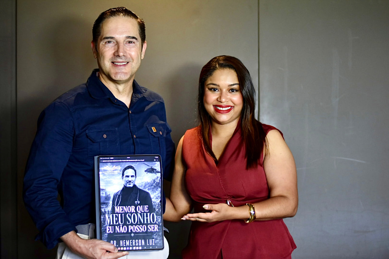 Dr. Hemerson Luz com uma convidada apresentando o livro em um tablet